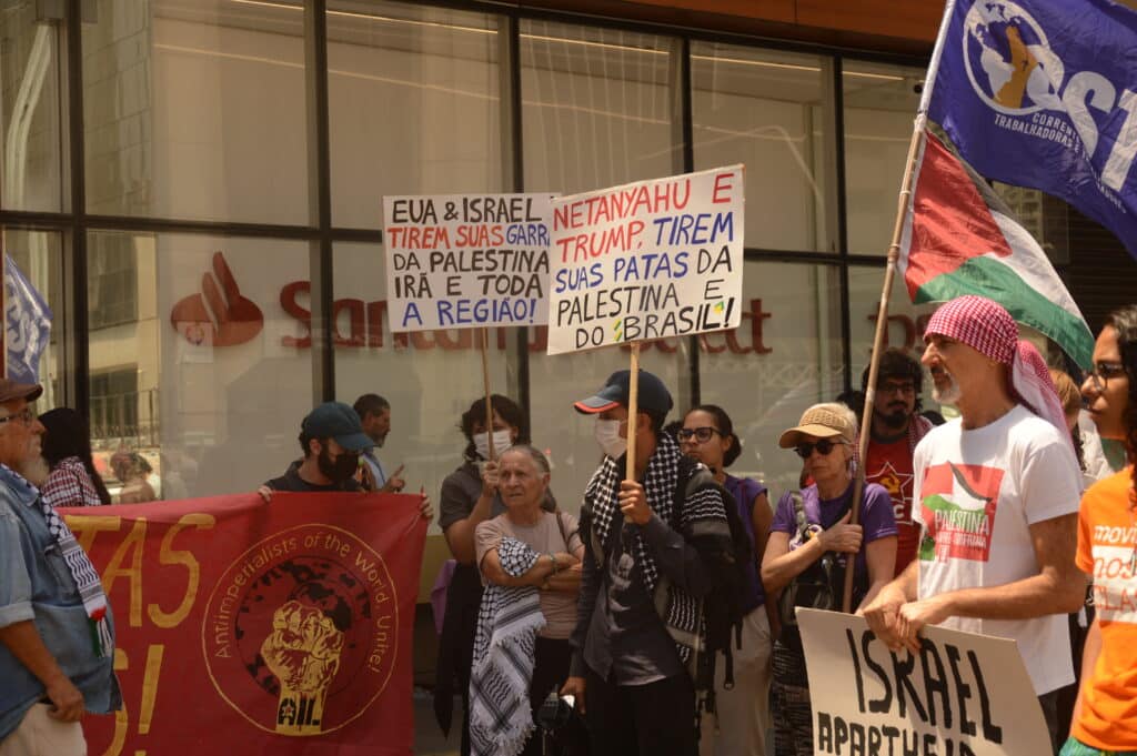 Manifestantes reunidos com cartazes contra o governo de EUA e Israel